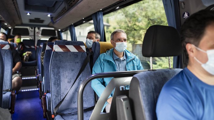 Keine Neuausschreibung der Lizenzen für Mietwagenunternehmer Menschen mit Schutzmasken sitzen in einem Bus mit sozialen Distanzmaßnahmen