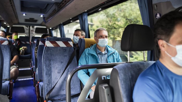 Mietwagenunternehmer: "Die Kapazitäten wären vorhanden" Menschen mit Schutzmasken sitzen in einem Bus mit sozialen Distanzmaßnahmen