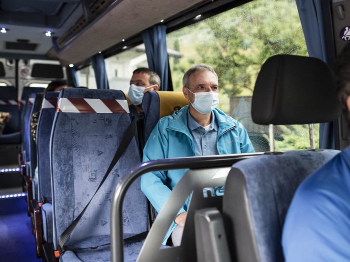 Keine Neuausschreibung der Lizenzen für Mietwagenunternehmer Menschen mit Schutzmasken sitzen in einem Bus mit sozialen Distanzmaßnahmen
