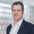 Sommerpraktika Porträt eines Mannes in weißem Hemd und dunklem Sakko vor unscharfem Hintergrund