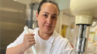 News Donna in giacca da cucina bianca mescola con bastone grande in contenitore metallico