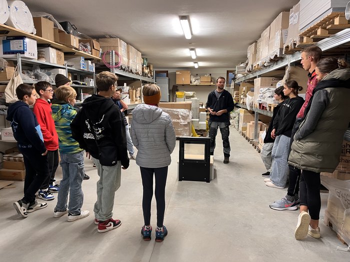 Artigianato come materia a scelta a Sarentino in autunno Gruppo di giovani ascolta un uomo in un magazzino