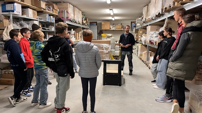 Wahlfach Sarntal im Herbst Gruppe von Jugendlichen hört in Lagerraum einem Mann zu