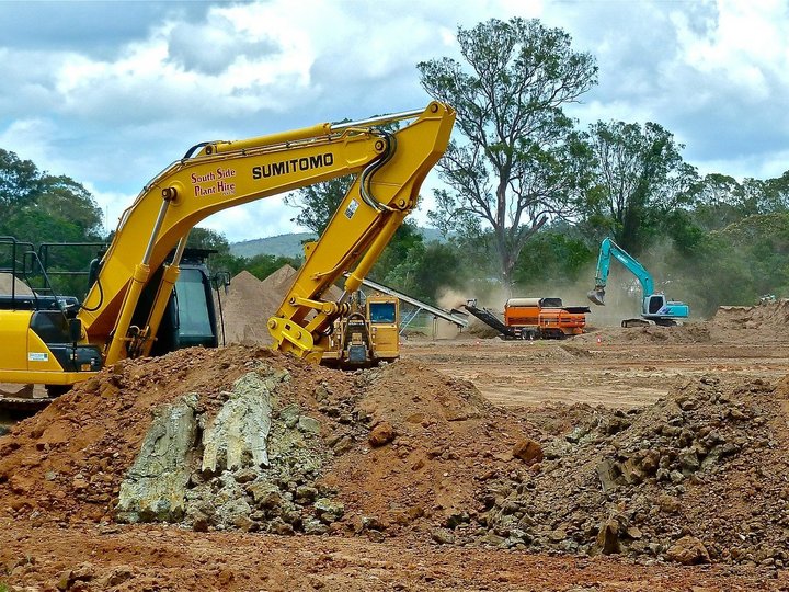 Imprese movimento terra Cantiere con escavatori giallo e blu, terra e alberi sullo sfondo