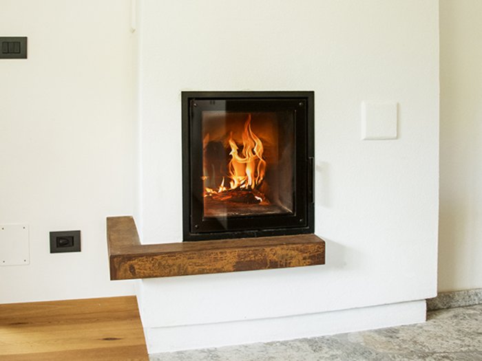 Kaminbrände vorbeugen Moderner Kamin mit brennendem Feuer in einem hellen Raum