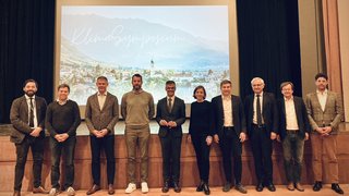 © Marktgemeinde Lana Gruppenfoto von zehn Personen auf Bühne vor Klimasymposium-Projektorbild