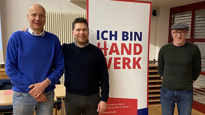 lvh-Ortsversammlung Bruneck: Ausblick auf vielversprechende Projekte und starke Zusammenarbeit Drei Männer stehen neben einem Plakat mit dem Text Ich bin Handwerk