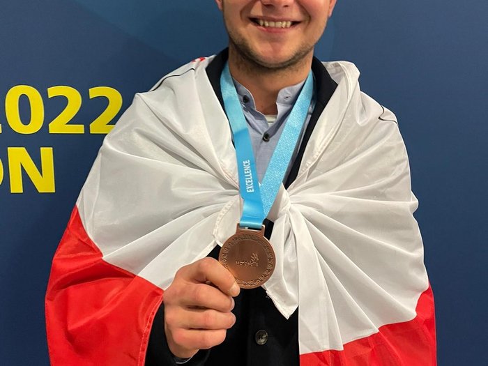 WorldSkills 2022: il Team Italy chiude con una Medallion for Excellence Giovane sorridente avvolto nella bandiera polacca con medaglia al collo