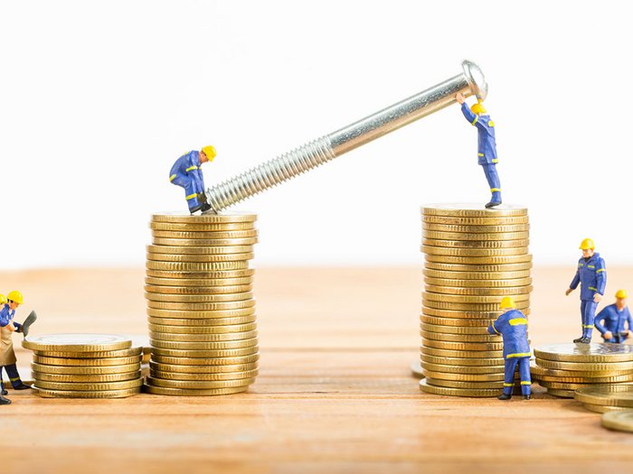 A fonte degli interessi elevati che minacciano le imprese, lvh.apa chiede di attivare i fondi di rotazione Operai in miniatura assemblano vite grande su pile di monete d'oro