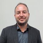 Imprese movimento terra Ritratto di uomo sorridente con barba corta e giacca davanti a parete chiara