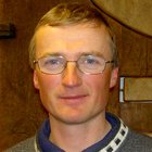 Maschinenschnitzer Porträt eines Mannes mit Brille und Pullover vor Holzhintergrund