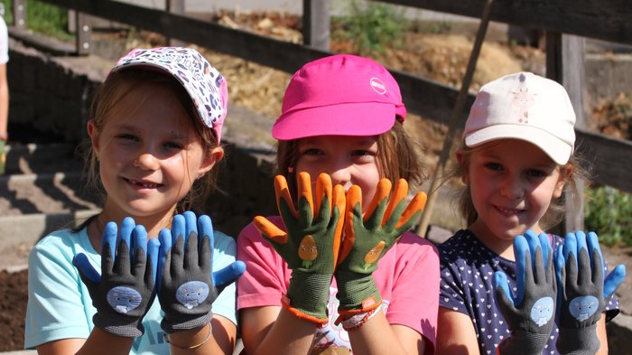 Blütenzauber und Gartenpracht: Das große Finale der KidsAcademy findet in Laimburg-Pfatten statt Drei Mädchen mit bunten Gartenhandschuhen zeigen ihre Hände nach vorne