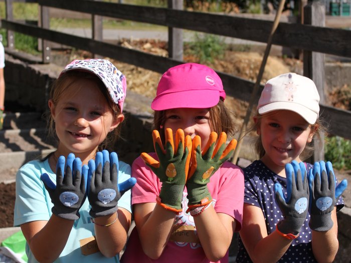 Blütenzauber und Gartenpracht: Das große Finale der KidsAcademy findet in Laimburg-Pfatten statt Drei Mädchen mit bunten Gartenhandschuhen zeigen ihre Hände nach vorne