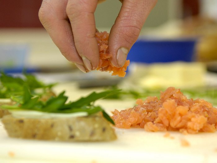 Ostern in Südtirol: Lebensmittelhandwerk überzeugt mit Qualität, Vielfalt und Tradition Hand bestreut Brot mit gehacktem Lachs und Kräutern