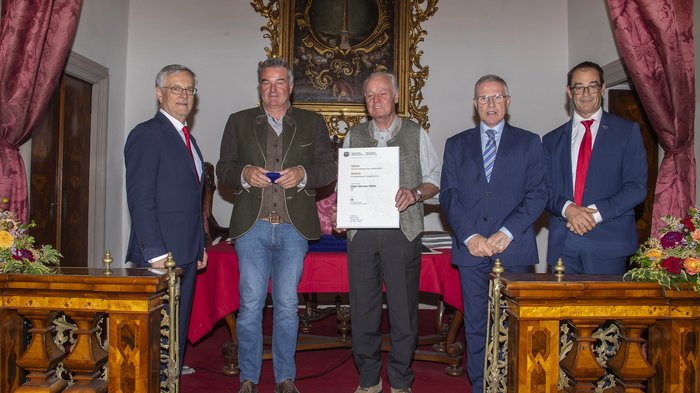 Südtiroler Wirtschaftspreis 2023: 6 Handwerksbetriebe des lvh ausgezeichnet Fünf Männer in Anzügen und Trachten empfangen Auszeichnung in einem barocken Saal