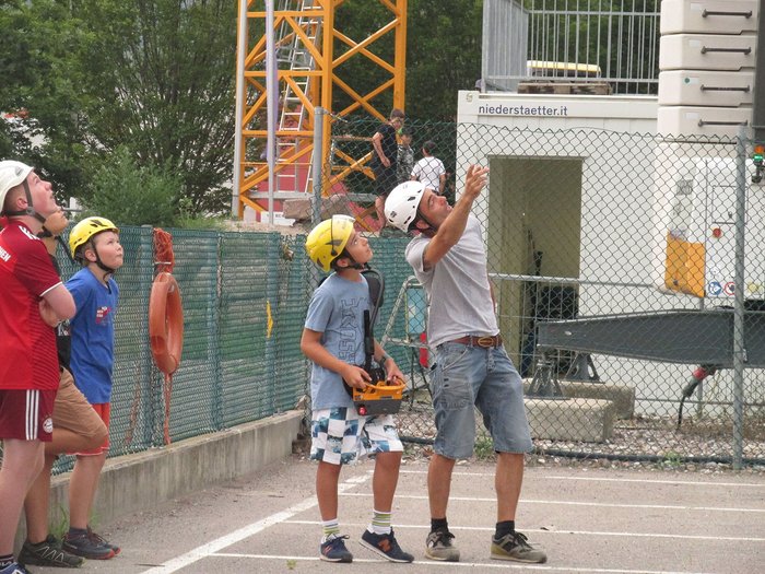Kinder und Jugendliche lernen die Welt der Baumaschinen Gruppe von Personen mit Helmen beobachtet etwas über ihnen auf einer Baustelle