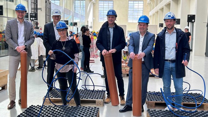 Einen Tag auf der Baustelle erleben Sechs Personen mit Schutzhelmen bei Vorführung von Bau- oder Installationsmaterial in Halle