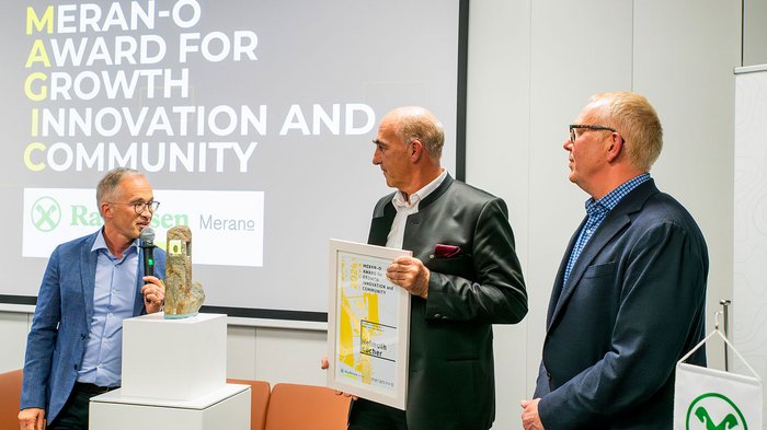 Assemblea generale annuale di lvh.apa insieme a hds Unione Cerimonia di premiazione Meran-O Award con tre uomini e trofeo su piedistallo