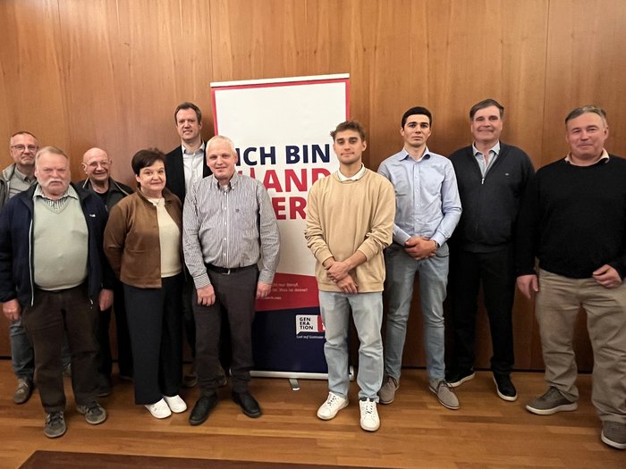 Artigianato forte in Bassa Atesina: scambio e prospettive chiare presso l’assemblea comunqle di Termeno Gruppo di dieci persone davanti a una parete in legno con uno striscione pubblicitario