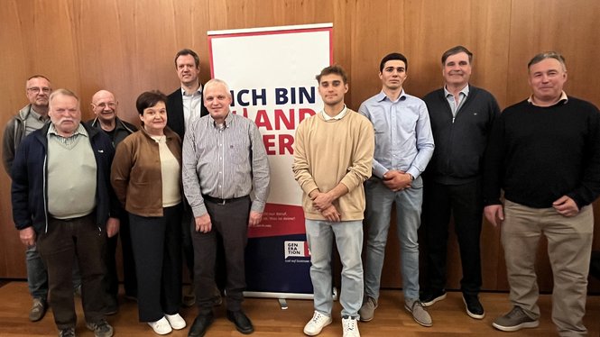 Home Gruppo di dieci persone davanti a una parete in legno con uno striscione pubblicitario