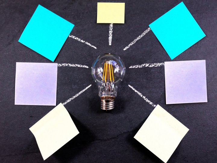 Sviluppo aziendale Lampadina al centro con foglietti colorati e linee su lavagna nera