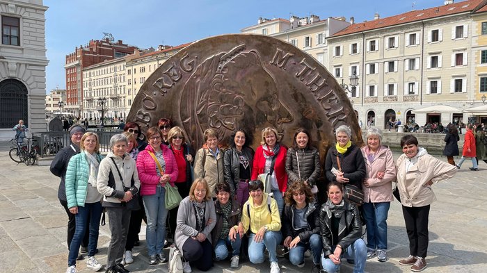 Triest, Miramare und Me(e)hr… Gruppe von Frauen vor großer Münzenskulptur auf einem Platz in der Stadt
