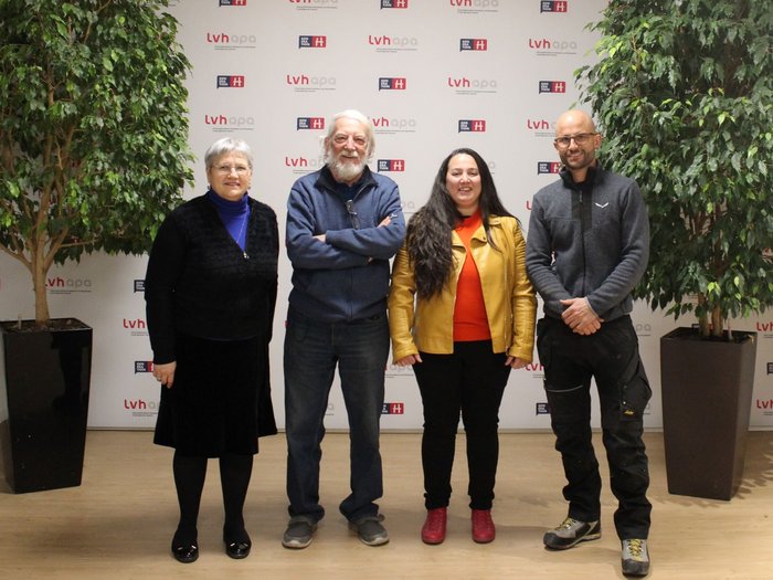Cambio al vertice dei gelatieri Quattro persone in piedi davanti a una parete con loghi LVH APA tra due grandi piante.