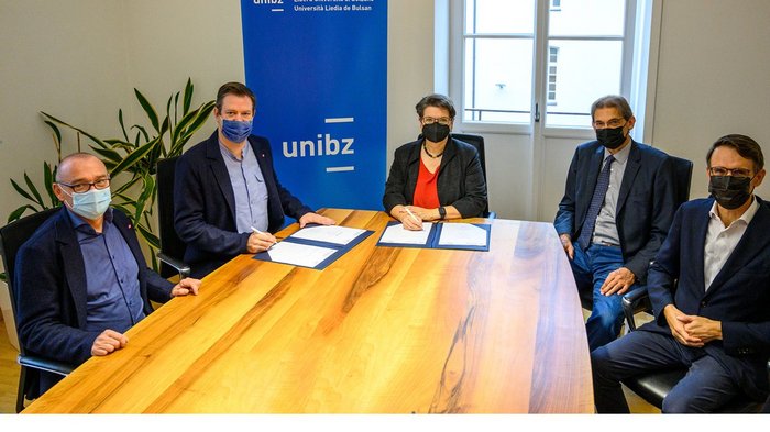 Handwerk trifft Uni Personen unterschreiben Dokumente bei der Freien Universität Bozen Sitzung