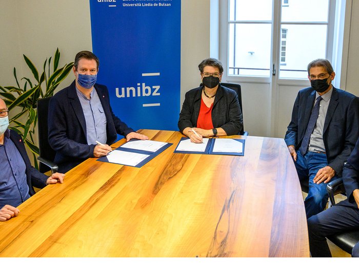 Handwerk trifft Uni Personen unterschreiben Dokumente bei der Freien Universität Bozen Sitzung