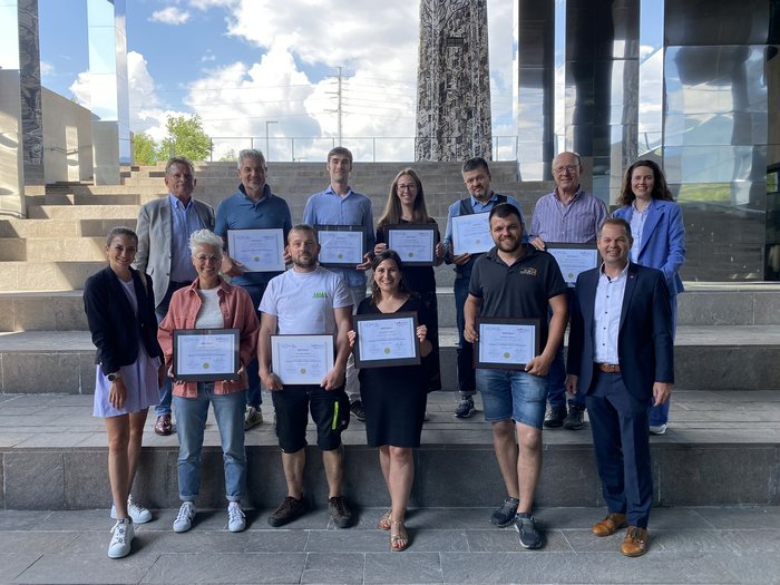 Zehn Beauftragte für Nachhaltigkeit in Südtiroler Handwerksbetrieben Gruppe von Menschen mit Zertifikaten auf einer Treppe bei einer Auszeichnung