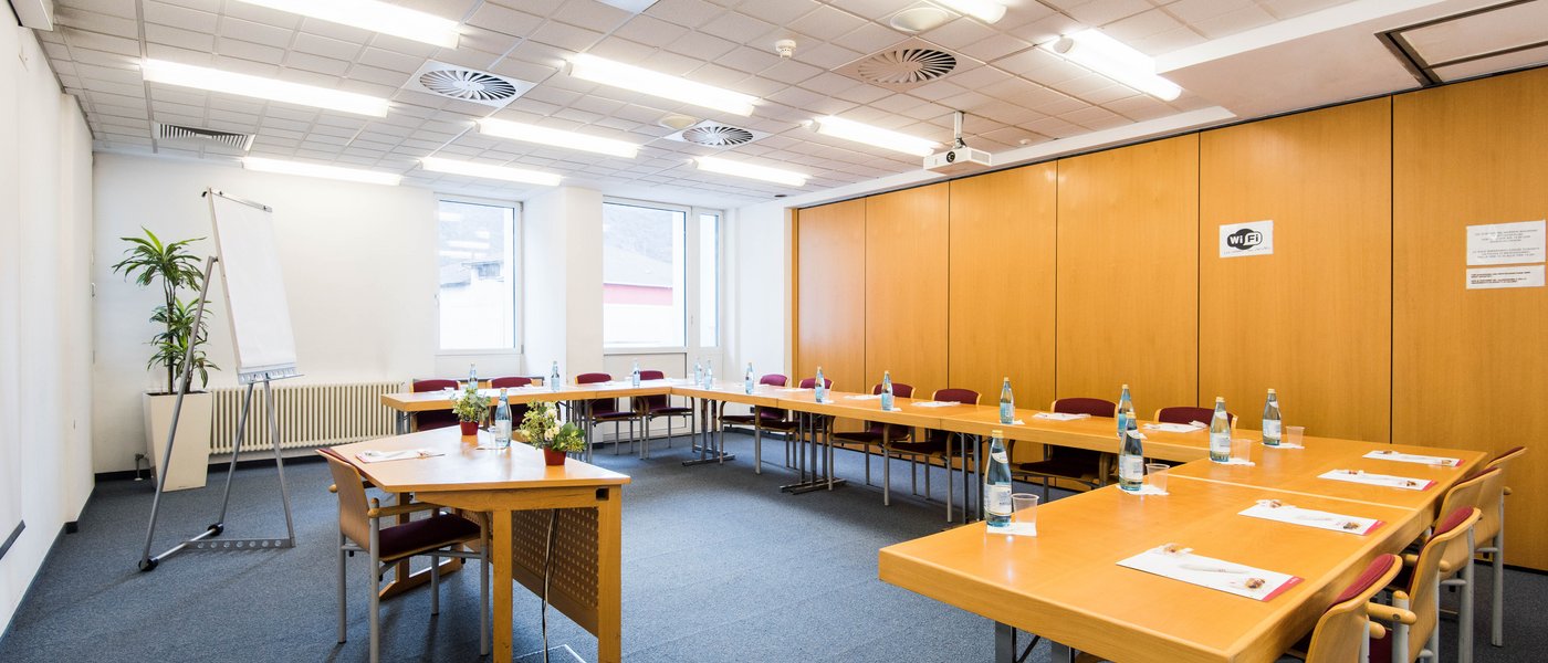 Vermietung Seminarräume Konferenzraum mit U-förmigem Tisch, Stühlen und Flipchart