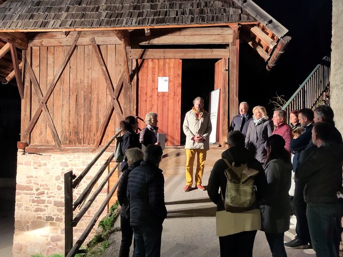 Nuovi percorsi per l’Alto Adige: La Piattaforma per il rurale continua a puntare sullo sviluppo sostenibile dei paesi Gruppo di persone ascolta una persona di notte davanti a un edificio in legno