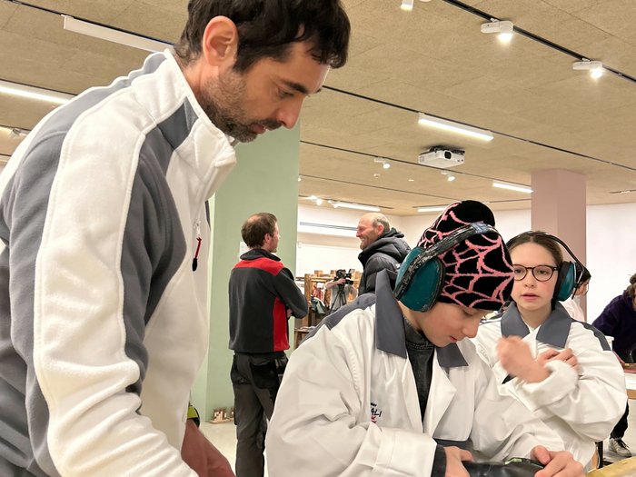 Handwerk hautnah erleben: Praxis trifft Zukunft in Gröden Erwachsener beaufsichtigt Kind beim Schleifen mit Schleifmaschine in Werkstatt