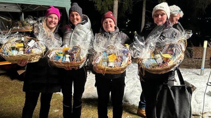 Lattlschießen der Handwerker/innen erfreut sich größter Beliebtheit Vier Frauen mit Geschenkkörben bei Nacht im Freien, Schnee im Hintergrund