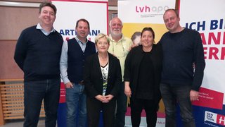 News Sechs Personen posieren vor Bannern bei einer Veranstaltung