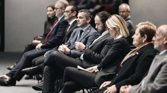 © Alan Bianchi Geschäftsleute in formeller Kleidung sitzen in einer Reihe bei einer Veranstaltung