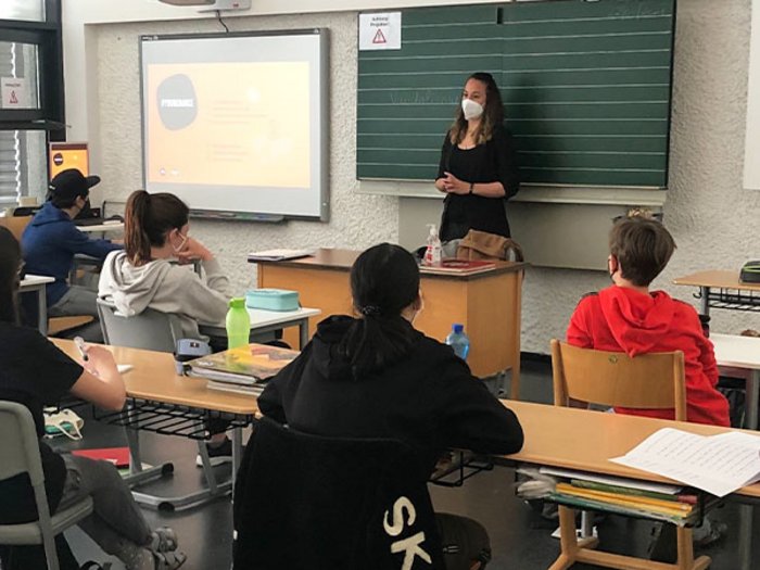 In die Welt der praktischen Berufe eintauchen Lehrerin mit Maske unterrichtet Schüler im Klassenzimmer mit Beamer