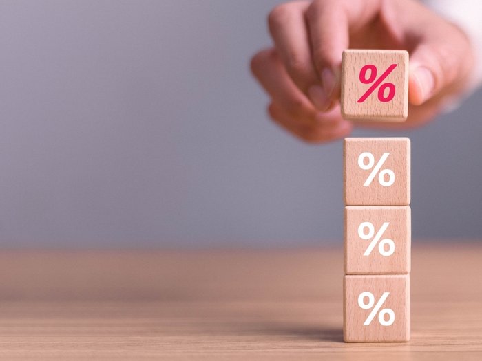 Iperammortamento: grandi opportunità per le imprese altoatesine Mano che impila cubi di legno con simbolo percentuale su tavolo