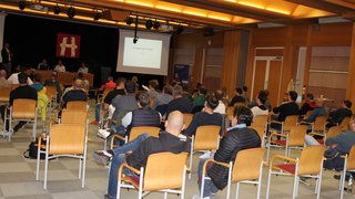 News Publikum bei einer Präsentation in einem Konferenzraum mit Holzbalkendecke