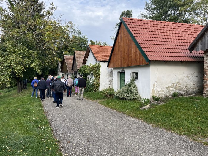 Althandwerker/innen unterwegs: Rundfahrt Weinviertel Gruppe von Menschen auf einem Weg neben kleinen Häusern mit roten Dächern