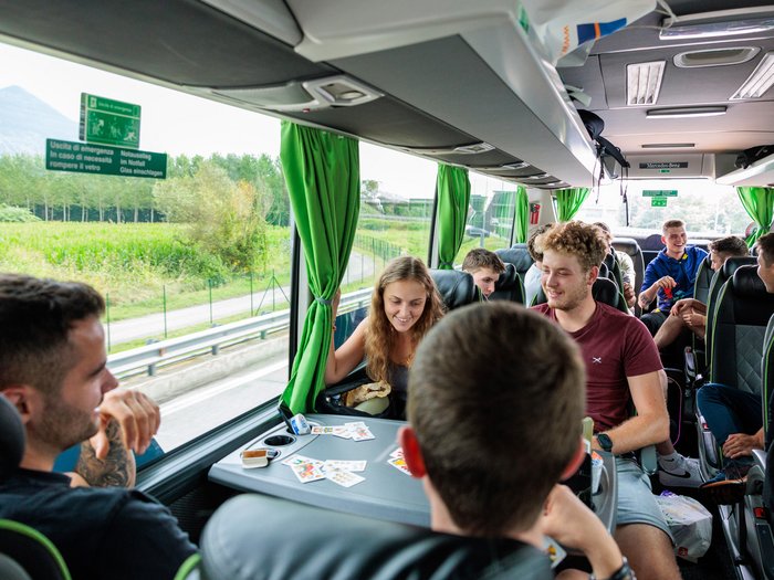 WorldSkills 2024 in Lyon am Start Junge Leute spielen Karten und unterhalten sich in einem Bus mit grünen Vorhängen