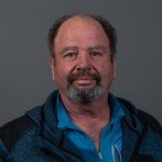 Untervinschgau Porträt eines Mannes mit Bart und blauem Hemd vor grauem Hintergrund