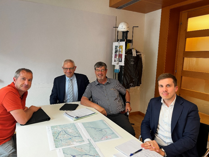 Dibattito sul Passo Resia: in primo piano percorsi alternativi e piani di risanamento Quattro uomini seduti a un tavolo in ufficio con mappe e appunti