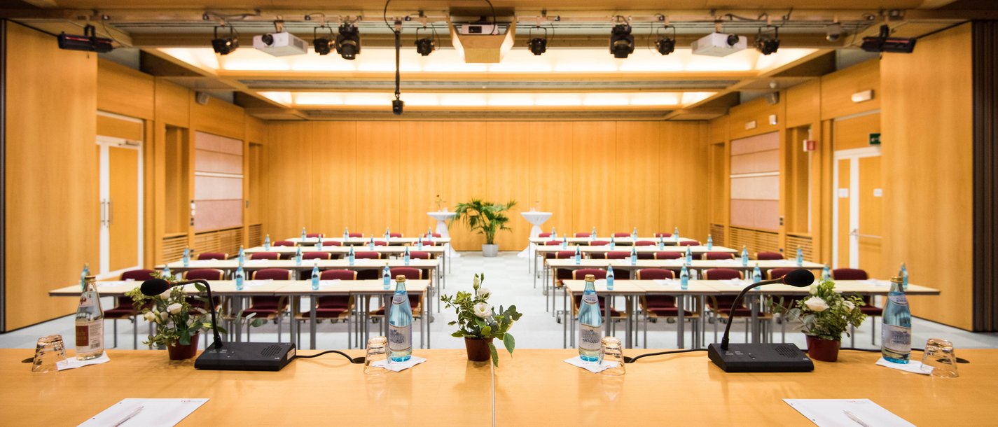 Affitto aule seminari Sala conferenze vuota con podio, microfoni e bottiglie d'acqua