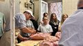 Praxis statt Theorie: Schulbesuche bei Handwerksbetrieben in St. Leonhard Menschen beobachten Fleischer bei der Fleischzerlegung auf einem Tisch