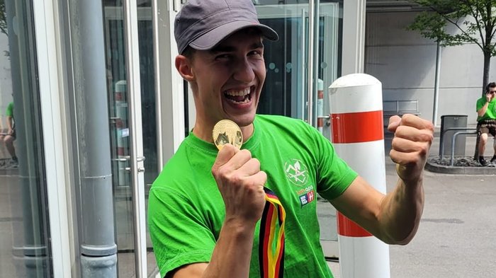 Foto 1 - Marcel Bolego © Südtiroler Zimmerer Junger Mann freut sich mit Medaille und grünem T-Shirt im Freien