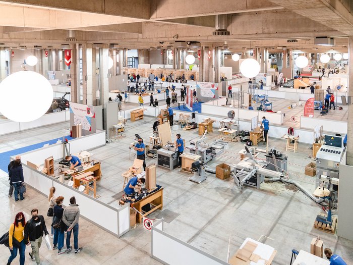 WorldSkills Italy: Junge Talente im Wettkampf Große Halle mit Handwerkern bei Bauarbeiten auf Werkbänken und Besuchern