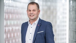 News Porträt eines Mannes im blauen Anzug vor verschwommenem Hintergrund