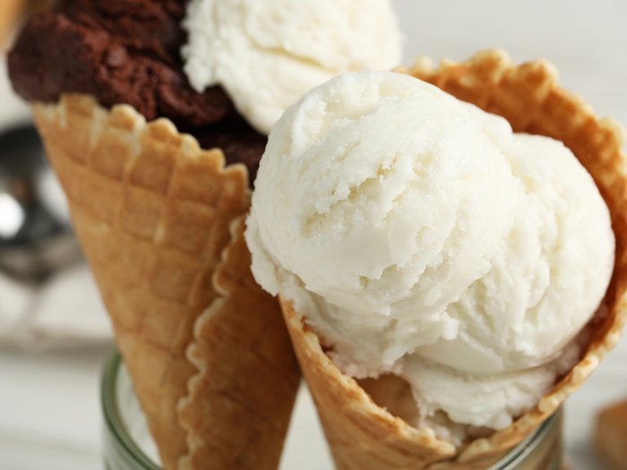 Warum der Frühling nach gutem Speiseeis schmeckt Zwei Waffel-Eistüten mit Vanille- und Schokoladeneis