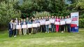 Consegna della spilla d’oro di lvh.apa Foto di gruppo di persone con certificati davanti a un banner Ich bin Handwerk all'aperto